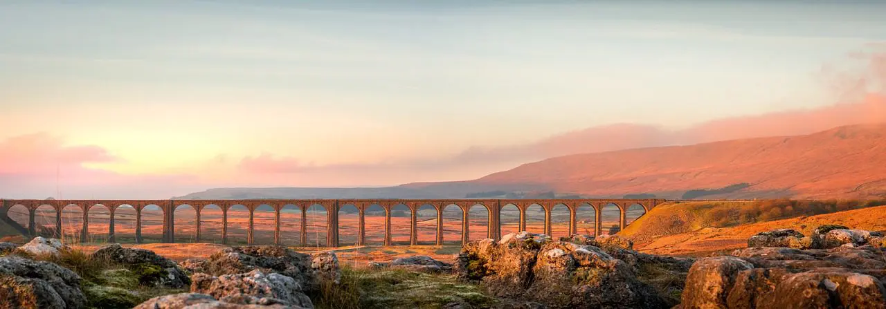 Historic Ribblehead Viaduct in Yorkshire Dales at sunrise, showcasing the UK’s countryside beauty and heritage for expats.
