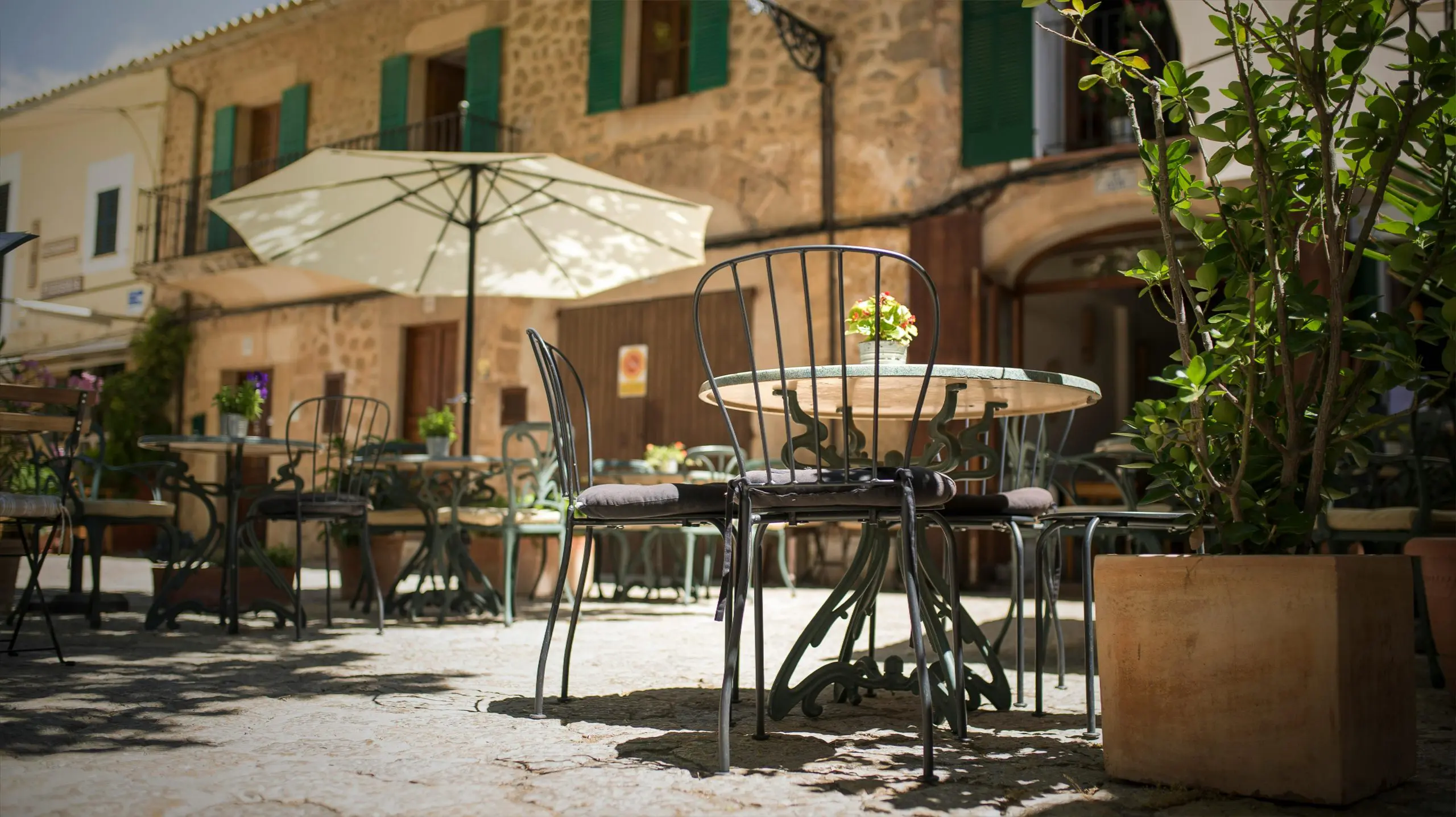 Charming outdoor café with iron chairs and stone buildings in Mallorca, Spain, symbolizing Mediterranean lifestyle and expat living.