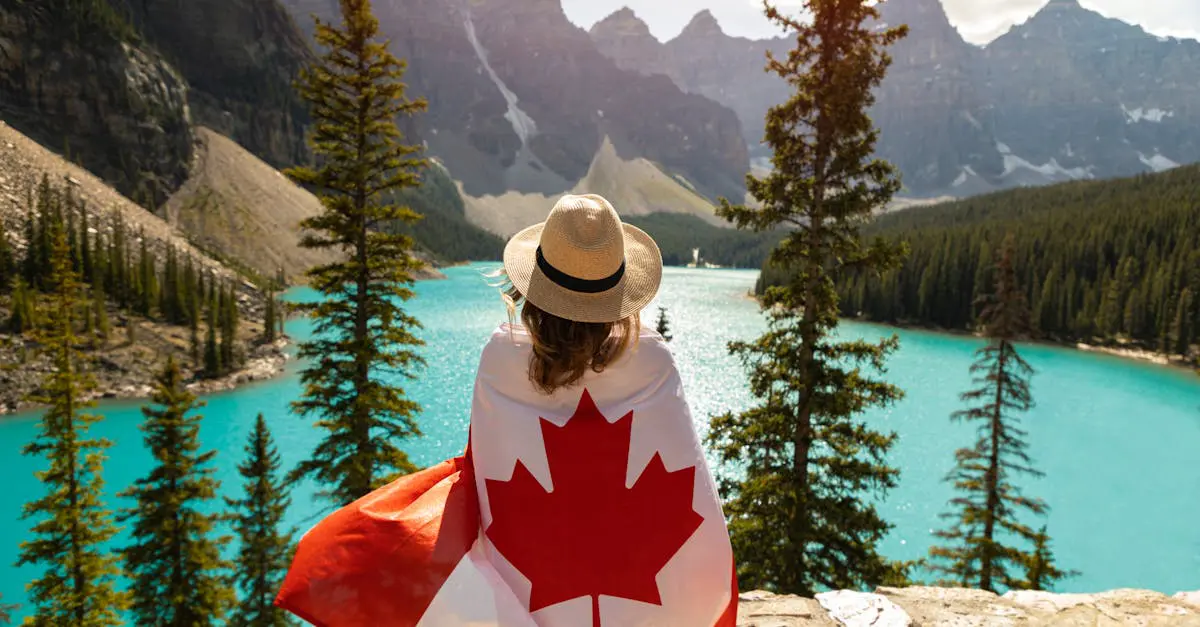 Person wrapped in a Canadian flag overlooking a turquoise mountain lake and forest, symbolizing freedom and adventure for expats moving to Canada.