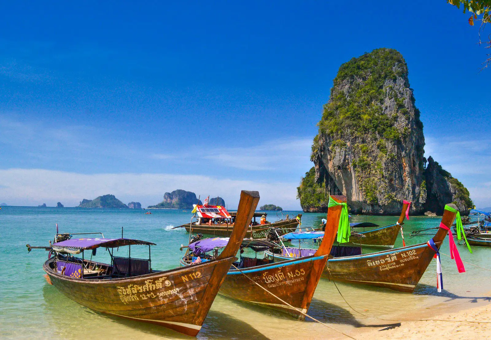 Long-tail boats on the beach in Krabi, Thailand, highlighting expat lifestyle and island travel destinations.