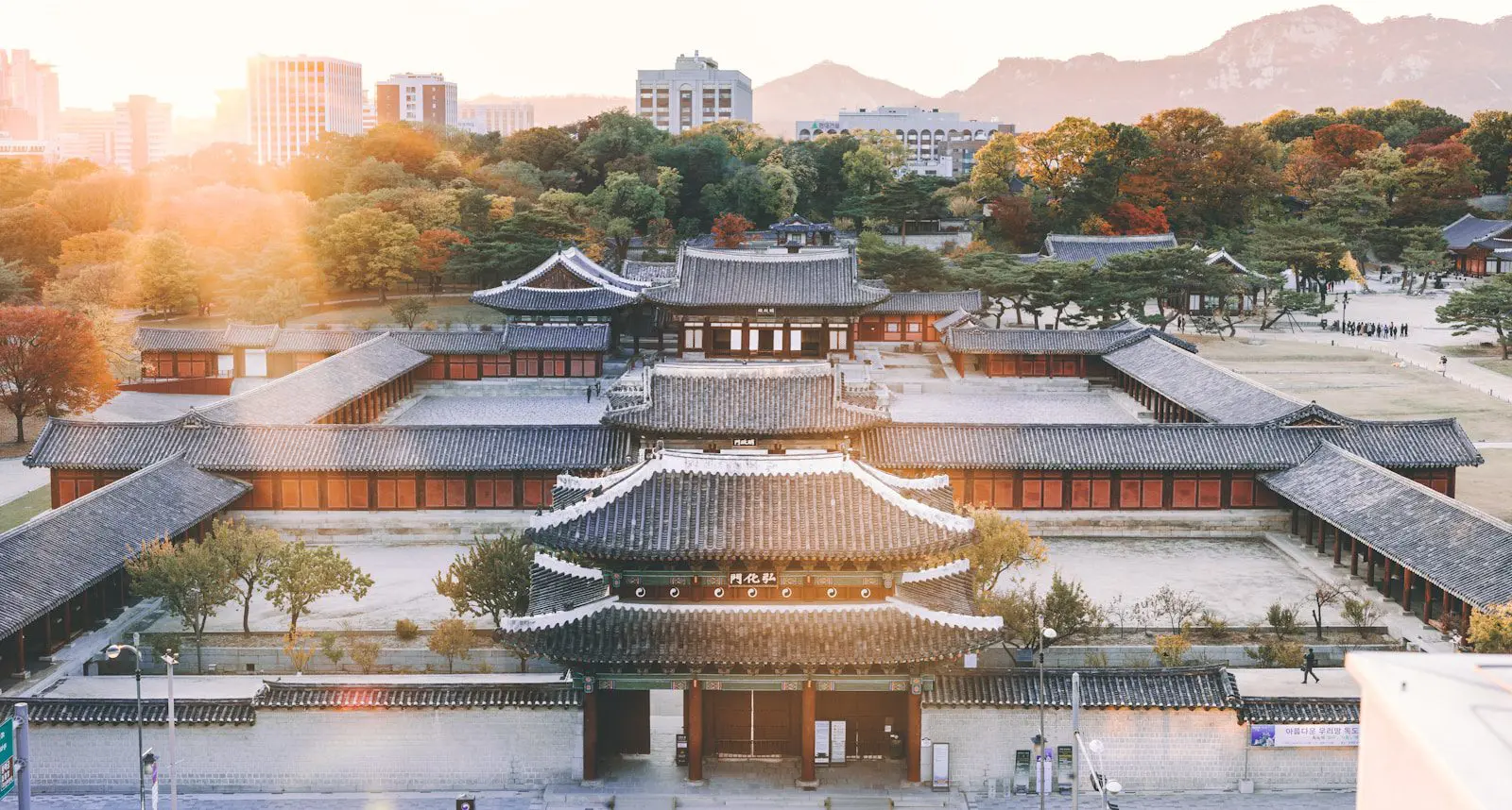 Aerial view of a traditional Korean palace complex in Seoul surrounded by autumn trees, reflecting cultural heritage and architecture.