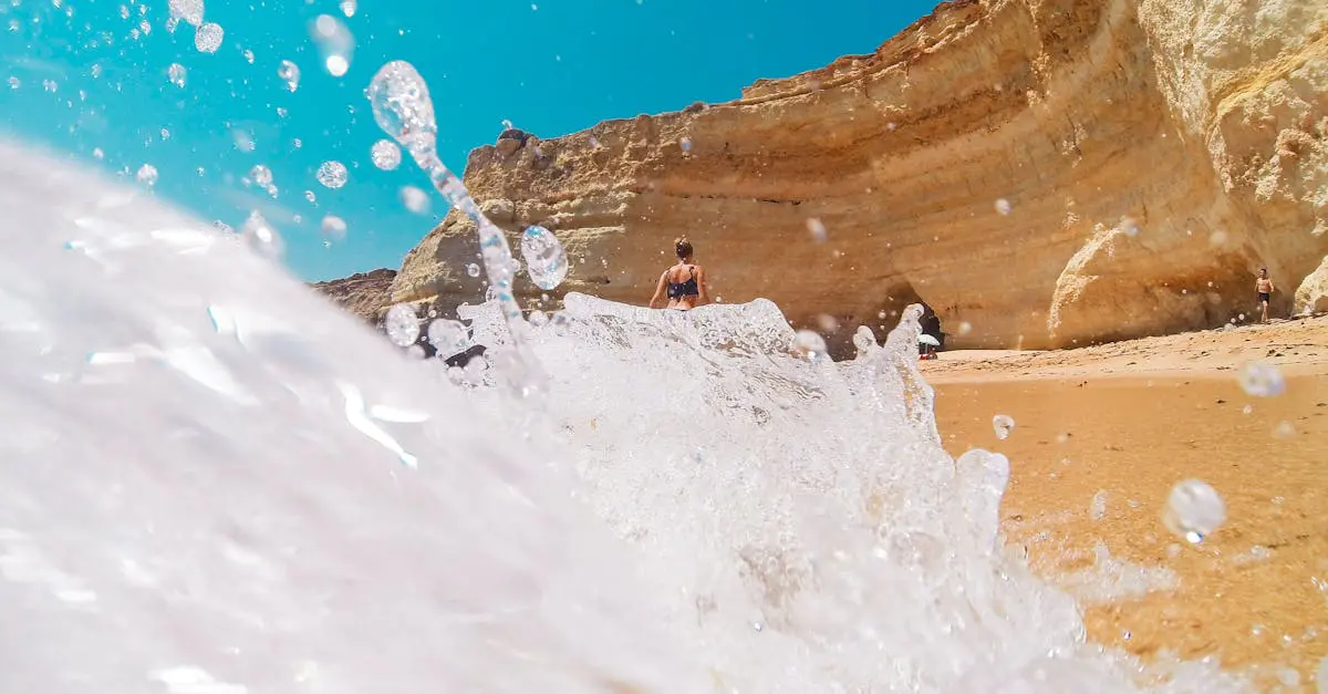 Waves splashing on golden cliffs at Algarve beach, Portugal symbolizing summer travel and coastal lifestyle for expats.
