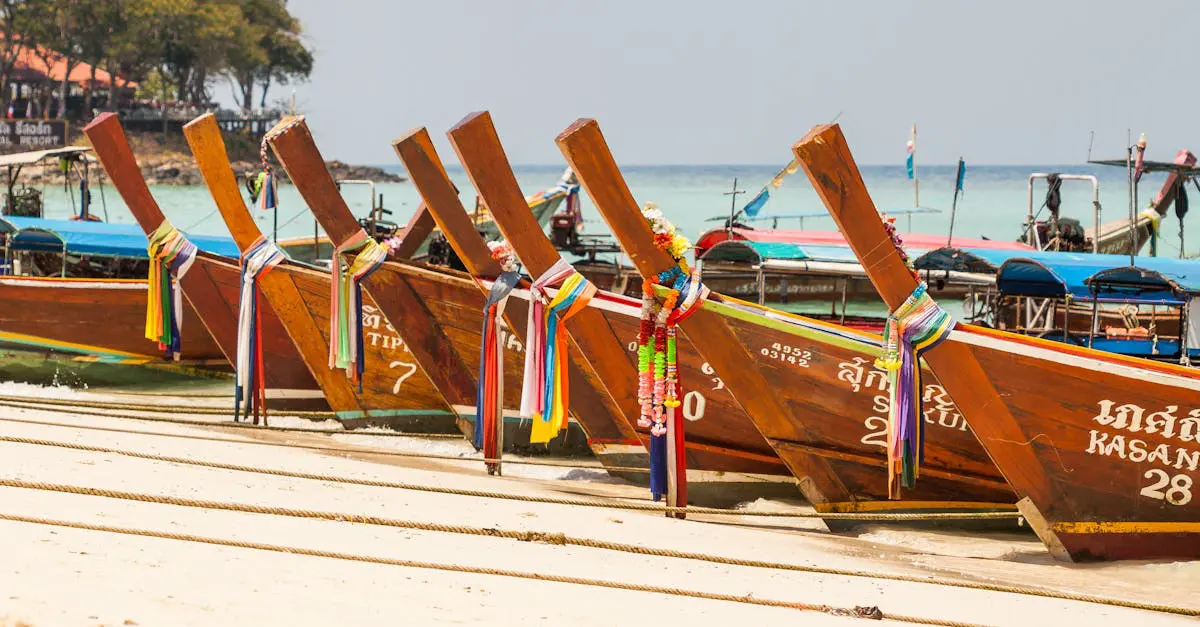 Traditional Thai longtail boats lined up on sandy beach with colorful ribbons, representing coastal travel in Thailand.