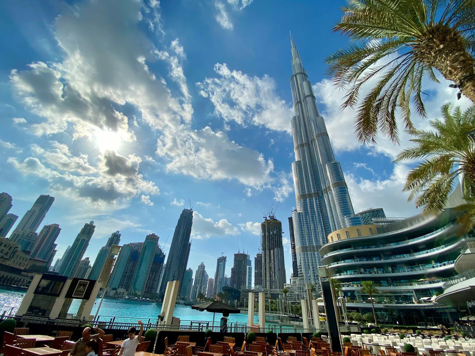 Burj Khalifa and Dubai Marina skyline under bright blue skies, showing modern architecture and waterfront dining areas.