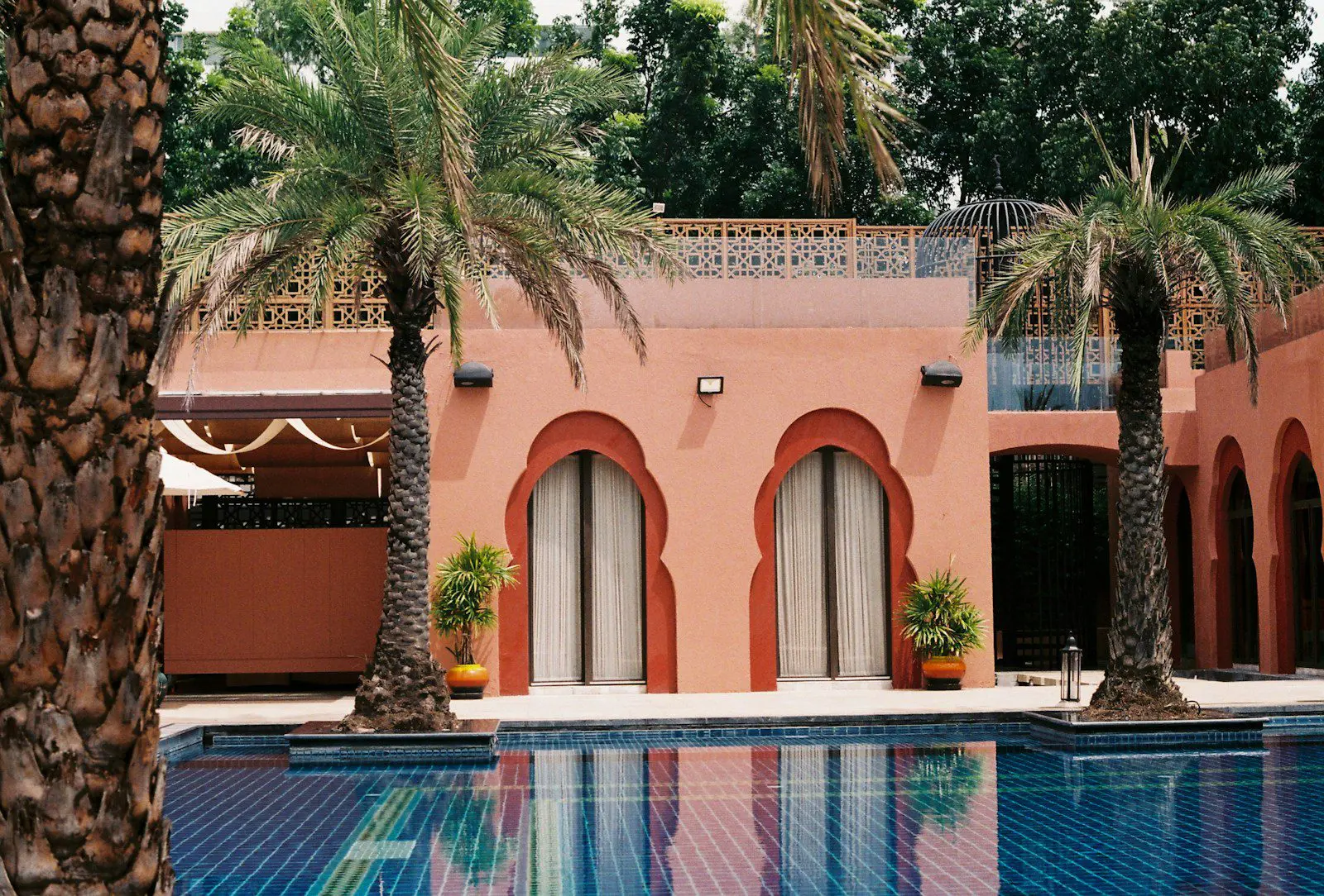 Luxurious Spanish villa with palm trees and blue-tiled pool, representing modern Mediterranean housing for expats.