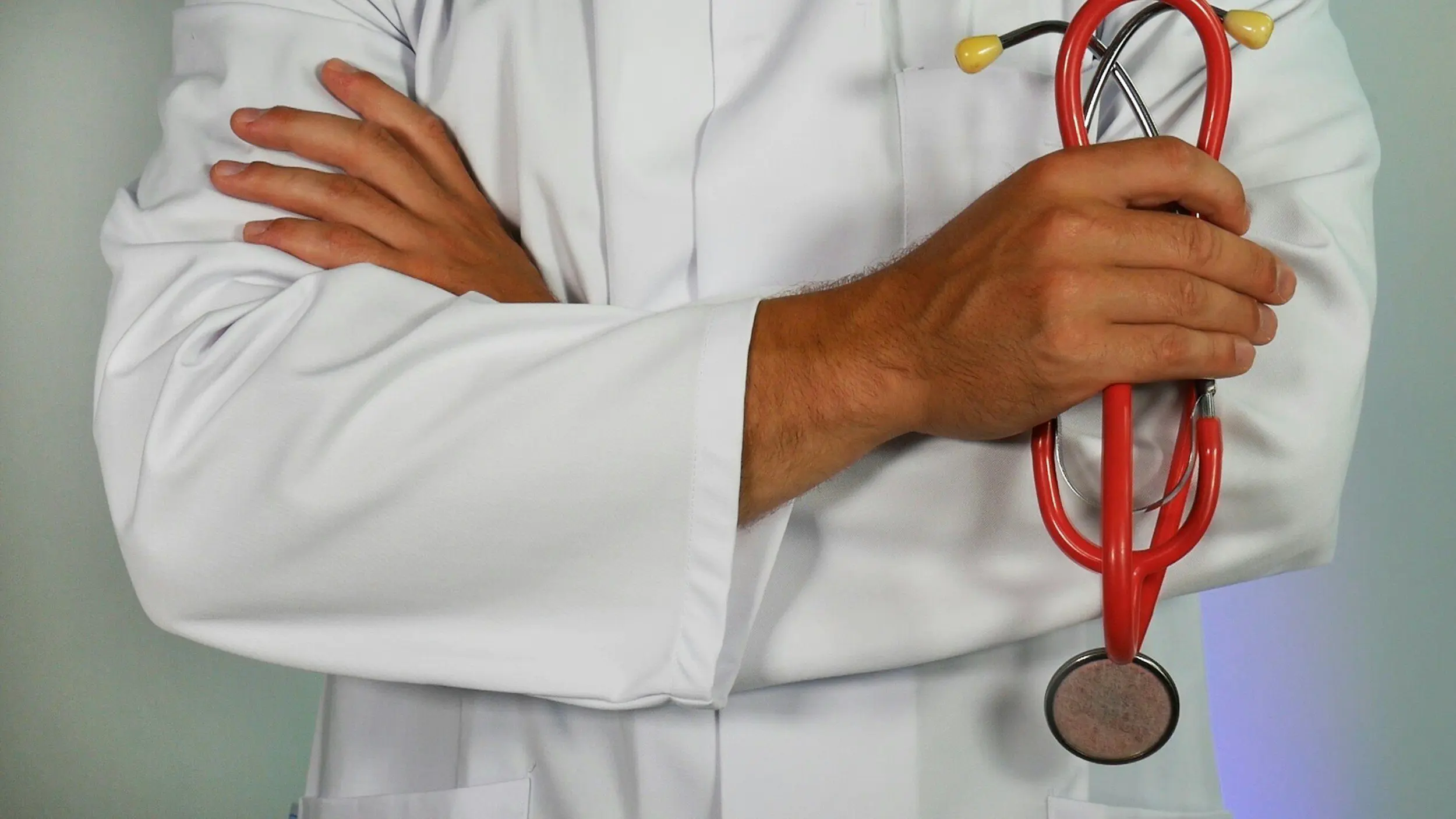 Doctor in a white coat holding a red stethoscope, symbolizing professional healthcare services and hospital care for expatriates.