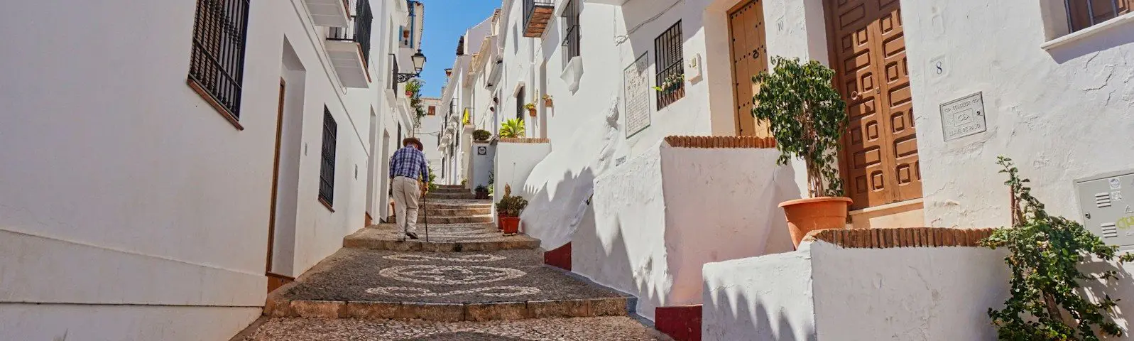 A cobblestone street lined with white buildings