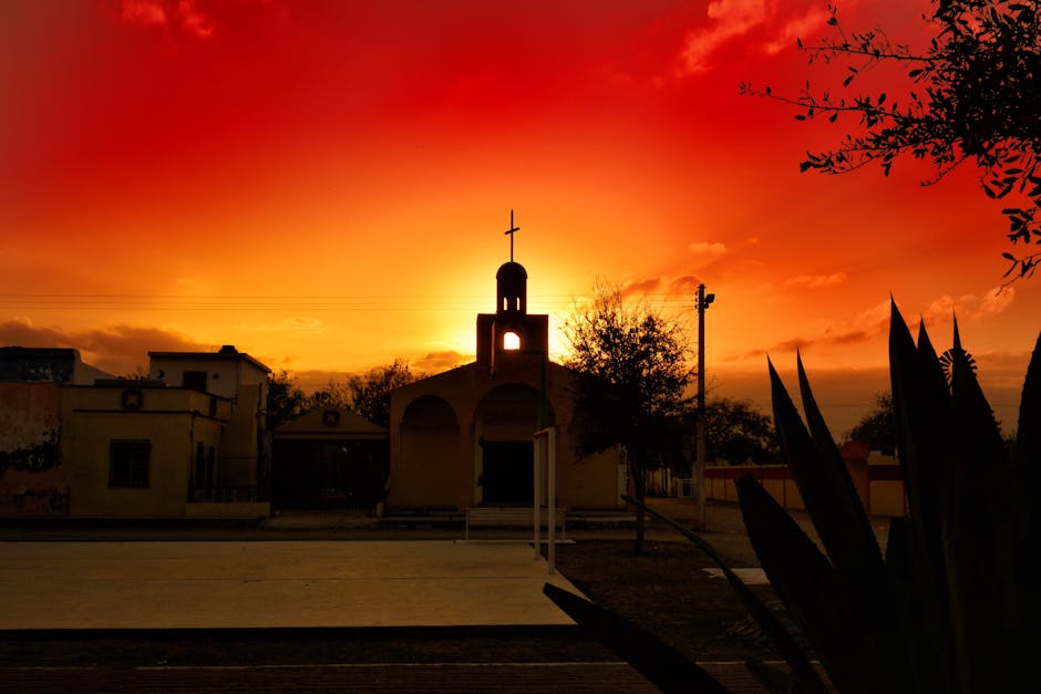 pexels-photo-415611-415611 Silhouetted church with a cross against a dramatic sunset sky, showcasing vibrant colors and cultural architecture.