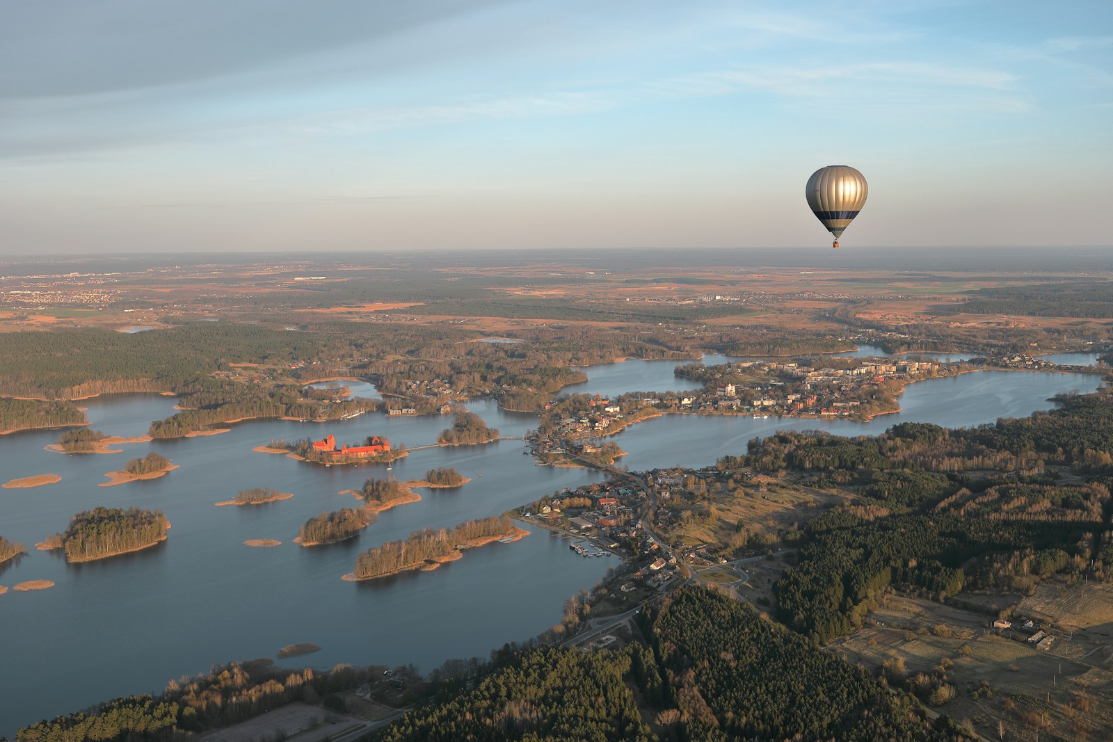 Photo by Maksim Shutov a hot air balloon flying over a large body of water