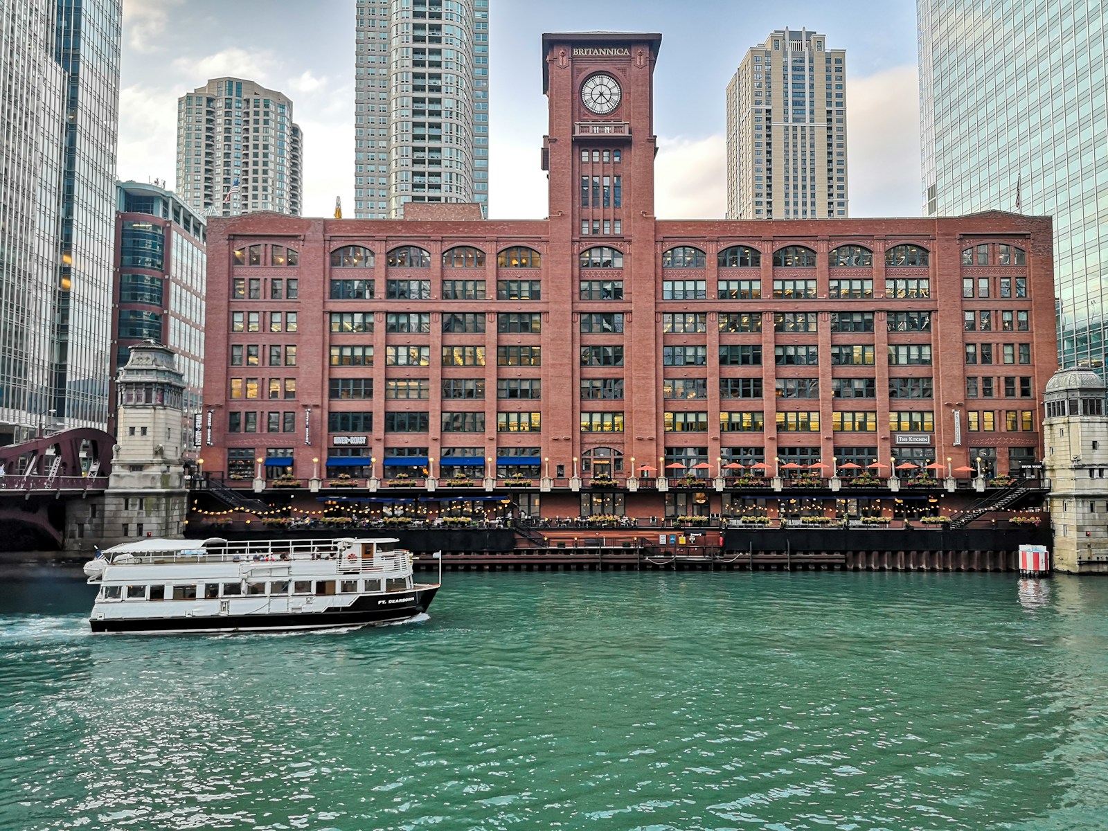 Photo by Toni Pomar a boat traveling down a river past a tall building
