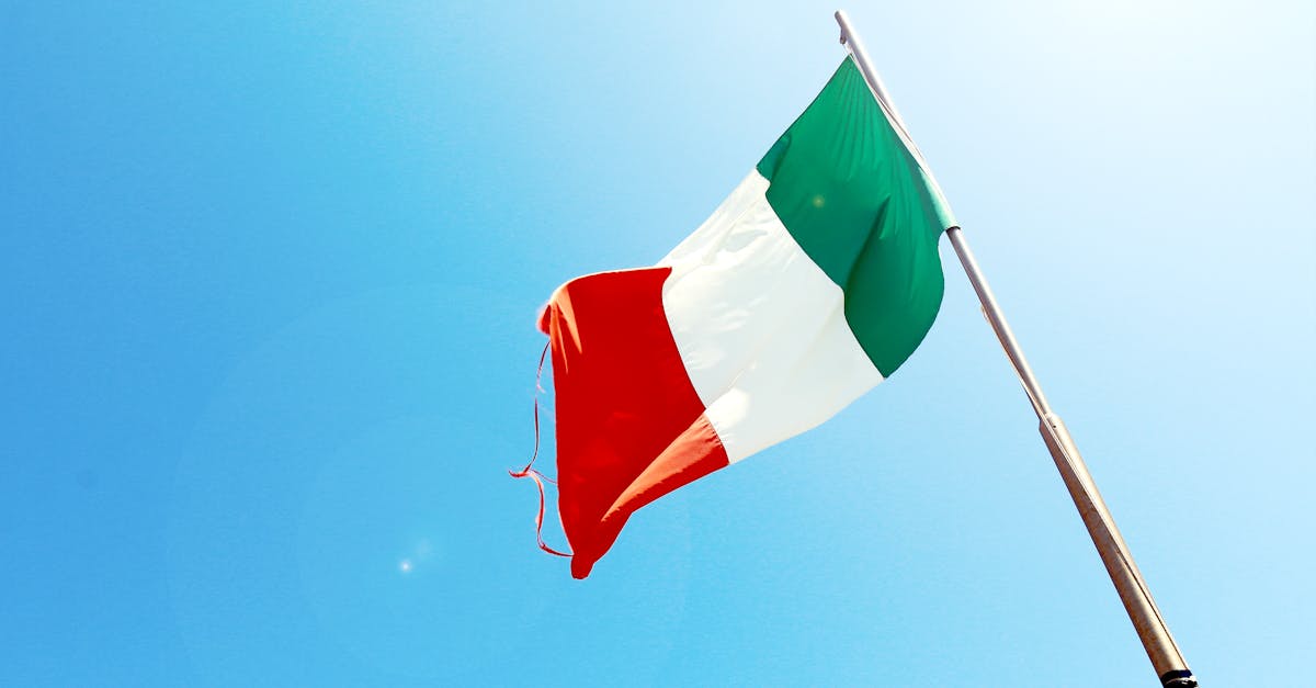 pexels-photo-7522 Vivid image of the Italian flag waving on a flagpole against a bright blue sky.