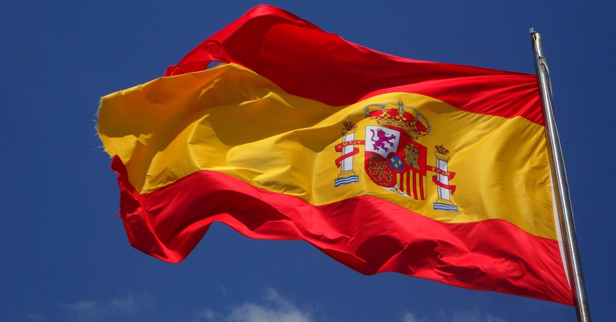 spain-flag-flutter-spanish-54097-54097 Vibrant Spanish flag waving against a clear blue sky and clouds.